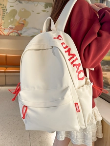 Minimalist white student backpack with red contrast details shown in a lifestyle setting