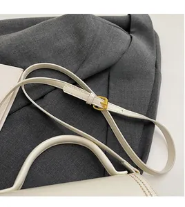 Detail of cream crossbody bag with adjustable shoulder strap and gold buckle hardware