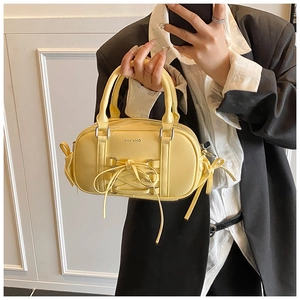 Detail of yellow glossy Boston bag with criss-cross ribbon and sweet bow decoration