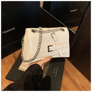 Détail du sac en cuir verni blanc avec chaîne argentée et boucles décoratives