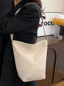 Chic cream bucket bag with gradient rhinestone embellishments shown on a shoulder