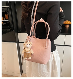 Pink lychee texture bucket bag with cute plush bear pendant on model in kitchen
