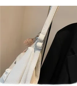 Detail of adjustable silver buckle and litchi texture on a white soft leather tote bag