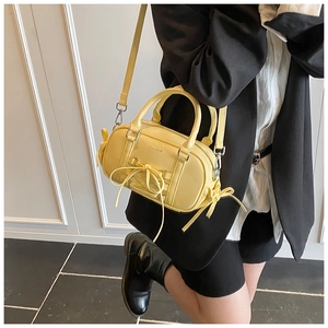 Detailed view of yellow leather Boston bag featuring a stylish bow knot accent