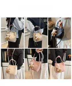 Model display of bucket bags in beige, black and pink with plush bear pendant