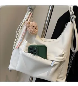 Detailed shot showing the front zip pocket of the white tote bag holding a smartphone