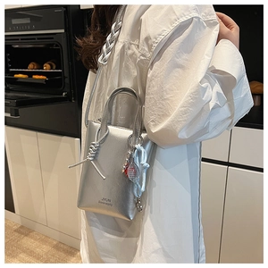 Silver metallic tote bag detail with thick rope strap and tennis racket charm accessory