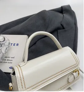 Detailed side view of white leather handbag with gold diamond stitching and hardware