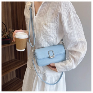Close-up of light blue litchi grain leather crossbody bag with silver oval buckle and strap