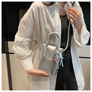 Close-up of a metallic silver mini crossbody phone bag with tennis racket charm detail