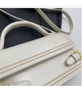 Detailed close-up of cream leather handbag with floral stitching and adjustable strap