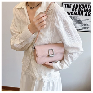 Detailed view of pink textured crossbody bag featuring a silver U-shaped metal buckle