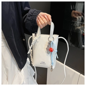 Detail of white leather bucket bag with JYUN logo and creative tennis racket charm