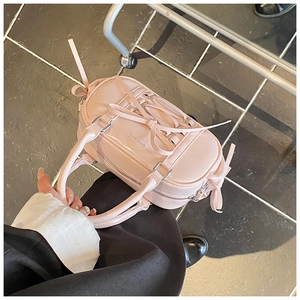 Detail of pink patent leather Boston bag with ribbon bows and silver logo plaque