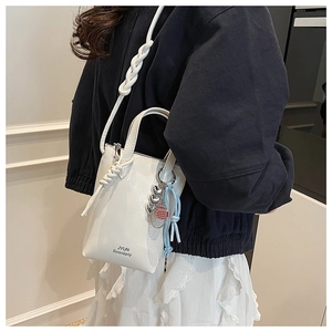 Close-up of a white leather crossbody bag with JYUN Serendipity print and woven strap