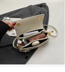 Interior view of white leather crossbody bag with multiple compartments and gold hardware