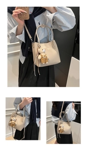 Detail of cream apricot bucket bag with lychee texture, featuring a cute teddy bear charm
