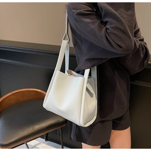 Detailed close-up of light gray lychee grain leather bucket bag with fashion logo print