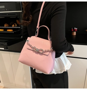 Detail of light pink crossbody bag with silver bow chain and elegant top handle