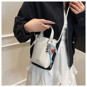 Detailed view of white bucket bag featuring JYUN logo and a blue tennis charm accessory