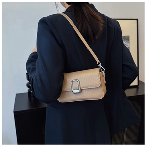 Detail of lychee textured leather bag with silver oval metal buckle on a shoulder bag