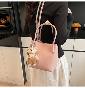 Pink lychee texture bucket bag with a cute plush bear pendant shown in a kitchen setting