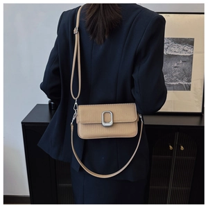 Detail view of khaki square crossbody bag with woven texture and silver metal clasp