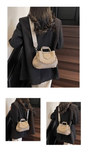 Detail of lychee textured bucket bag with metal handle and wide woven shoulder strap