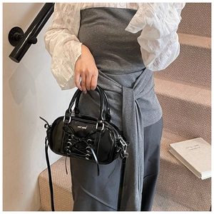 Detail of black ballet-style Boston bag with bow tie and glossy patent finish