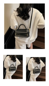 Detailed view of black leather square handbag with double buckle straps and metal studs