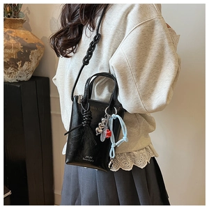 Detail of minimalist black crossbody bag featuring a unique thick knot shoulder strap design