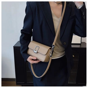 Detail of khaki textured leather crossbody bag with silver buckle worn by a model