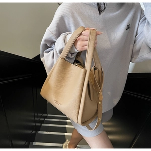 Detail view of beige lychee texture bucket bag with gold rivets and detachable strap