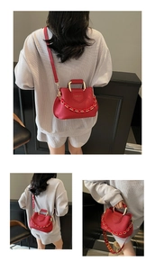 Detail of red lychee leather bucket bag with gold circular handle and two style straps