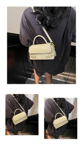 Detail of cream crossbody bag featuring golden buckle straps and smooth matte leather texture