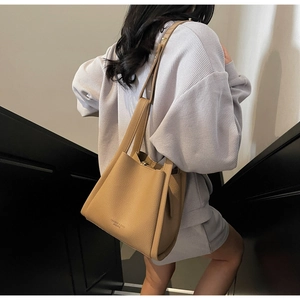 Detailed view of camel leather tote bag featuring lychee grain texture and embossed logo