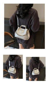 Detail of silver lychee pattern bucket bag featuring metal handle and gold chain strap