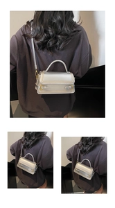 Detail of silver matte bag featuring unique yellow stitching and gold buckle straps