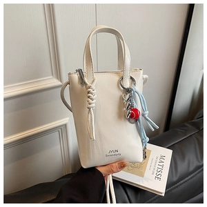 Close-up of white lychee leather handbag with JYUN lettering and heart charm decoration