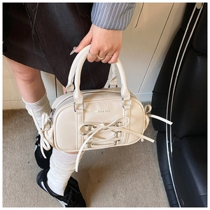 Detail of cream ballet-style Boston bag with patent finish and lace-up bow accent