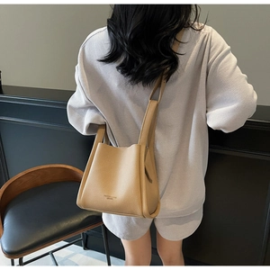 Detail of lychee pattern leather bucket bag in beige with handle and shoulder strap