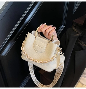 Detail of lychee pattern leather bucket bag with gold handle and acrylic chain strap