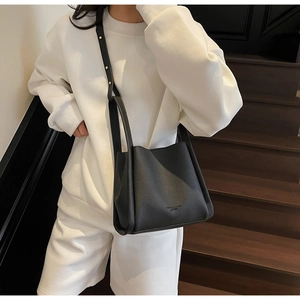 Detail of minimalist black lychee pattern leather tote with delicate shoulder strap