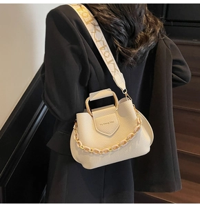 Detail view of beige lychee pattern bucket bag with U-shaped metal handle and wide strap