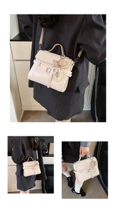 Detail of cream crossbody bag with pearl charms and bow accessory on model