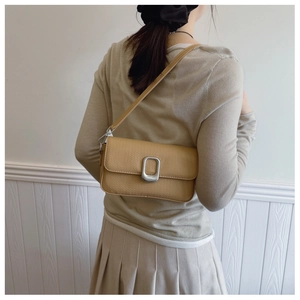 Litchi texture leather small square bag with large silver buckle worn by a model