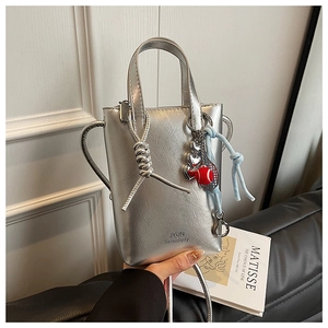 Detail of silver mini crossbody bag with JYUN logo and heart-shaped metal charm