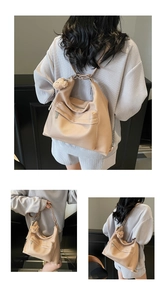 Detail of soft leather tote bag with plush bear charm and practical front zipper pocket