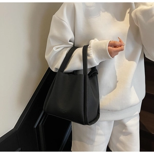 Detail of black litchi texture leather bucket bag with embossed logo and sturdy handle