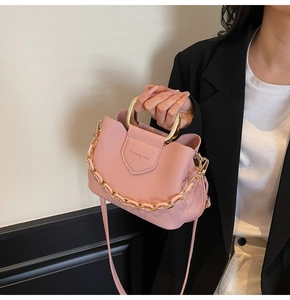 Detail of pink lychee leather bucket bag with gold circular handle and brand embossing